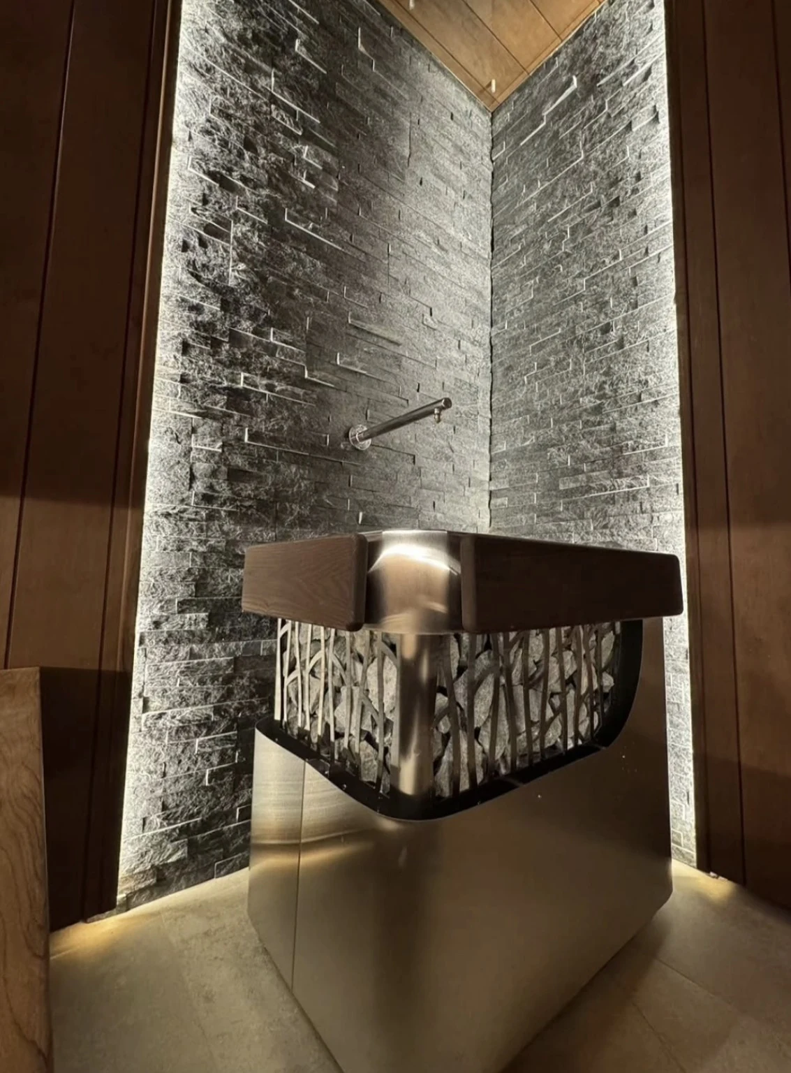 Metal water-delivery outlet above heater stones in the Flow & Steam sauna