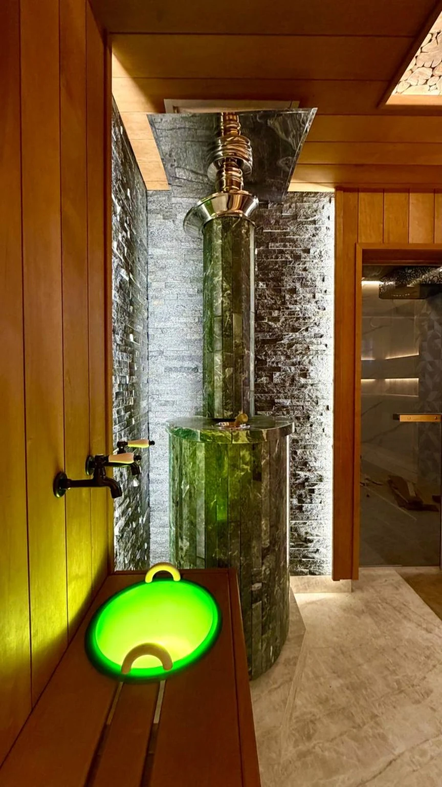 Wood-burning sauna heater with chimney and illuminated textured surround