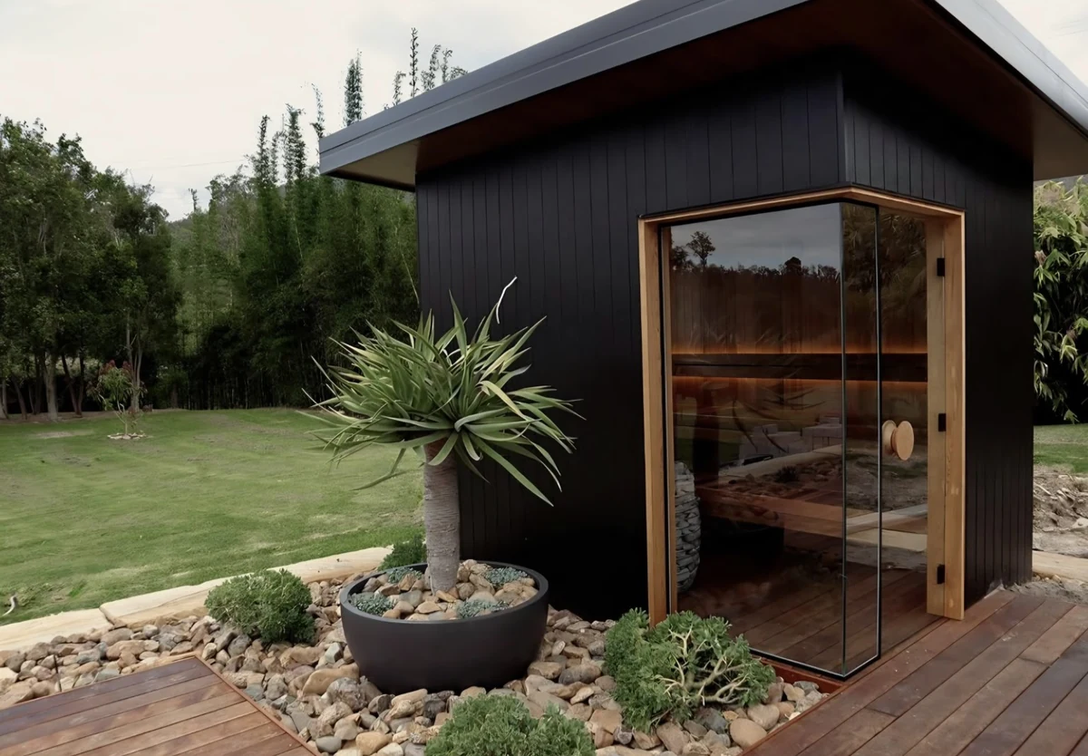 Dark timber Garden Ember outdoor sauna glowing at dusk