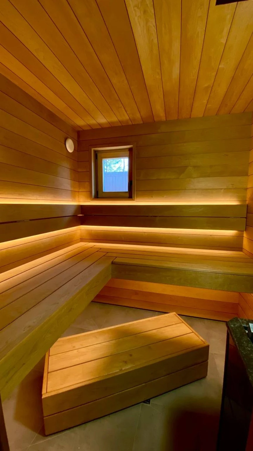Finished sauna with wraparound benches, a small window and freestanding step