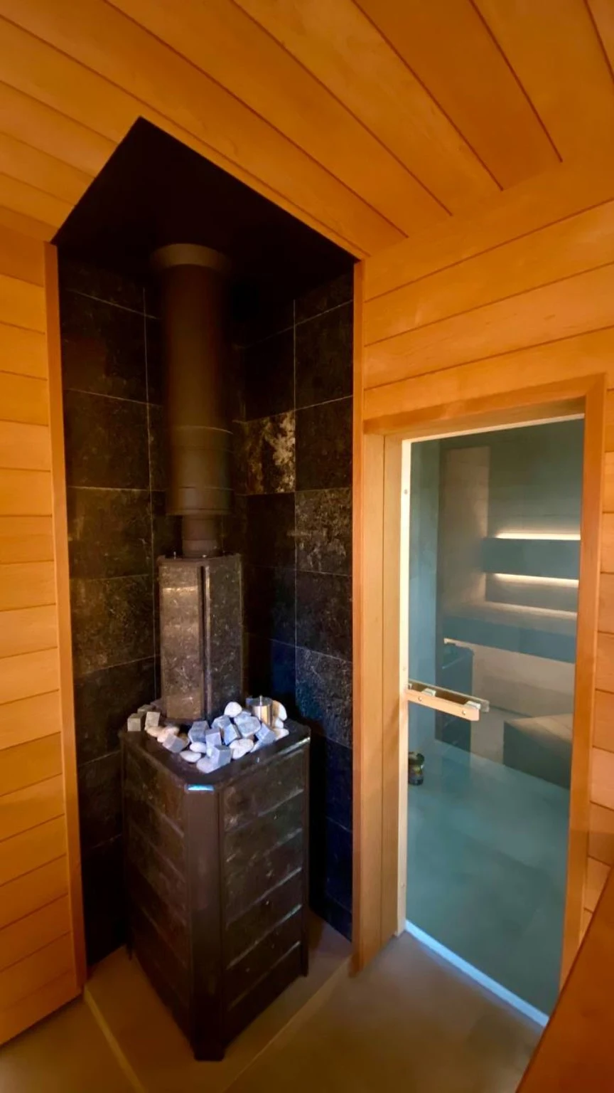 Wood-burning heater and black chimney within a dark stone-lined recess