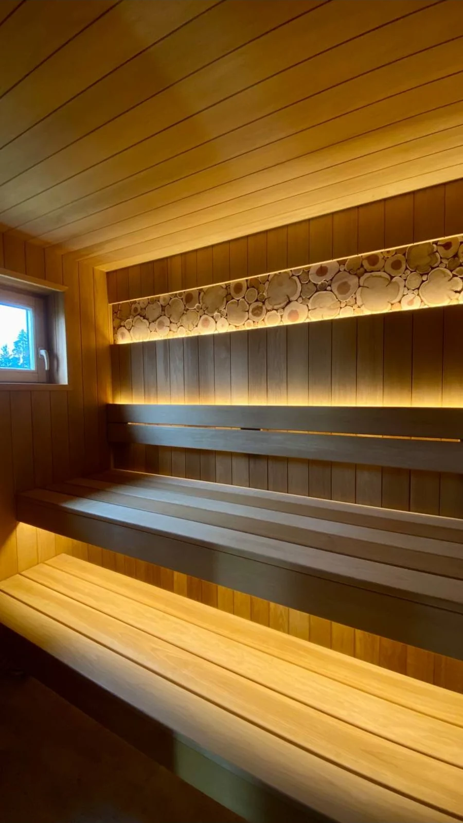 Finished mountain sauna near Boone with layered benches and illuminated wood-slice band