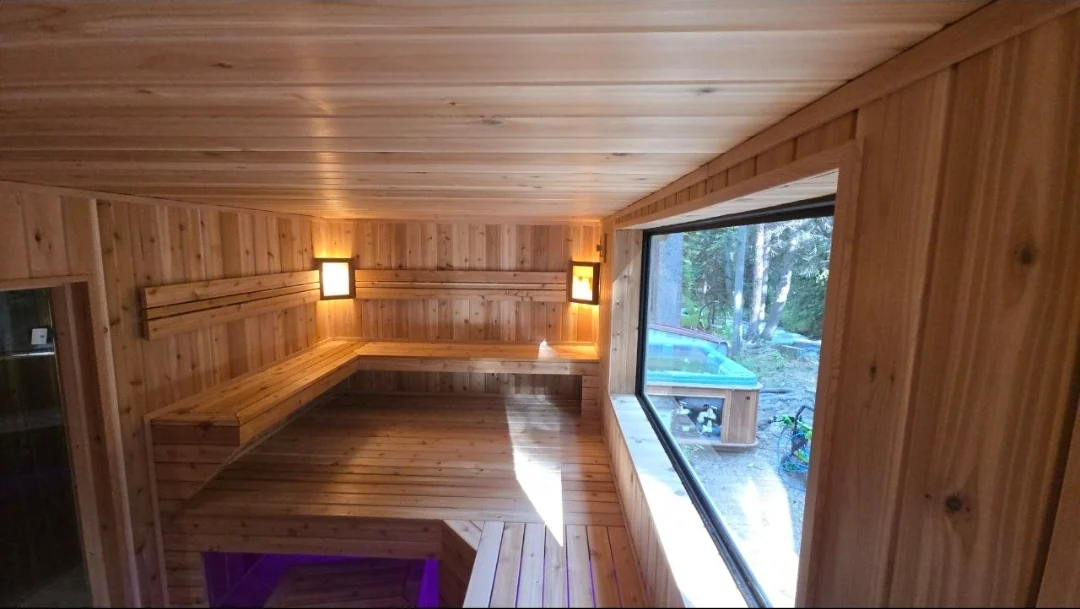 Finished sauna near Asheville with layered benches, wall lights and a large woodland-facing window