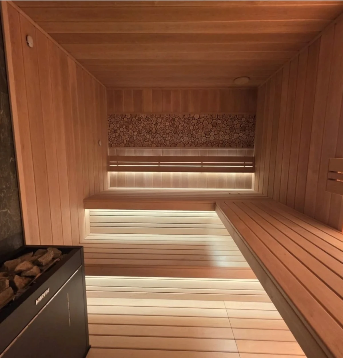 Sauna interior with multi-level benches and a decorative wood-end panel on the back wall