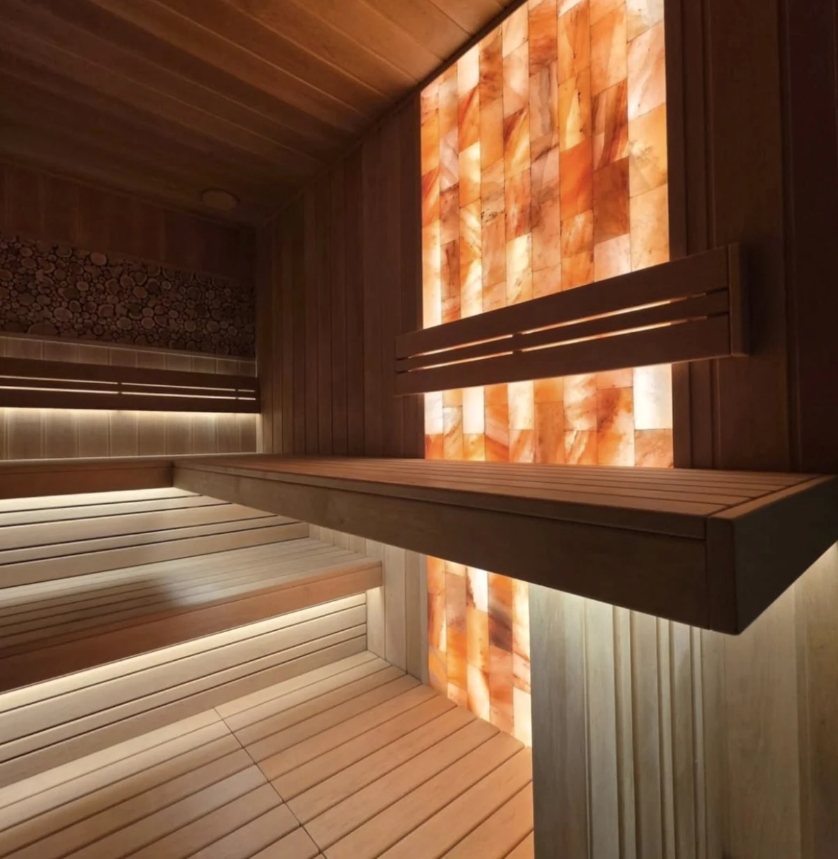 Wood sauna bench crossing an illuminated Himalayan salt feature wall