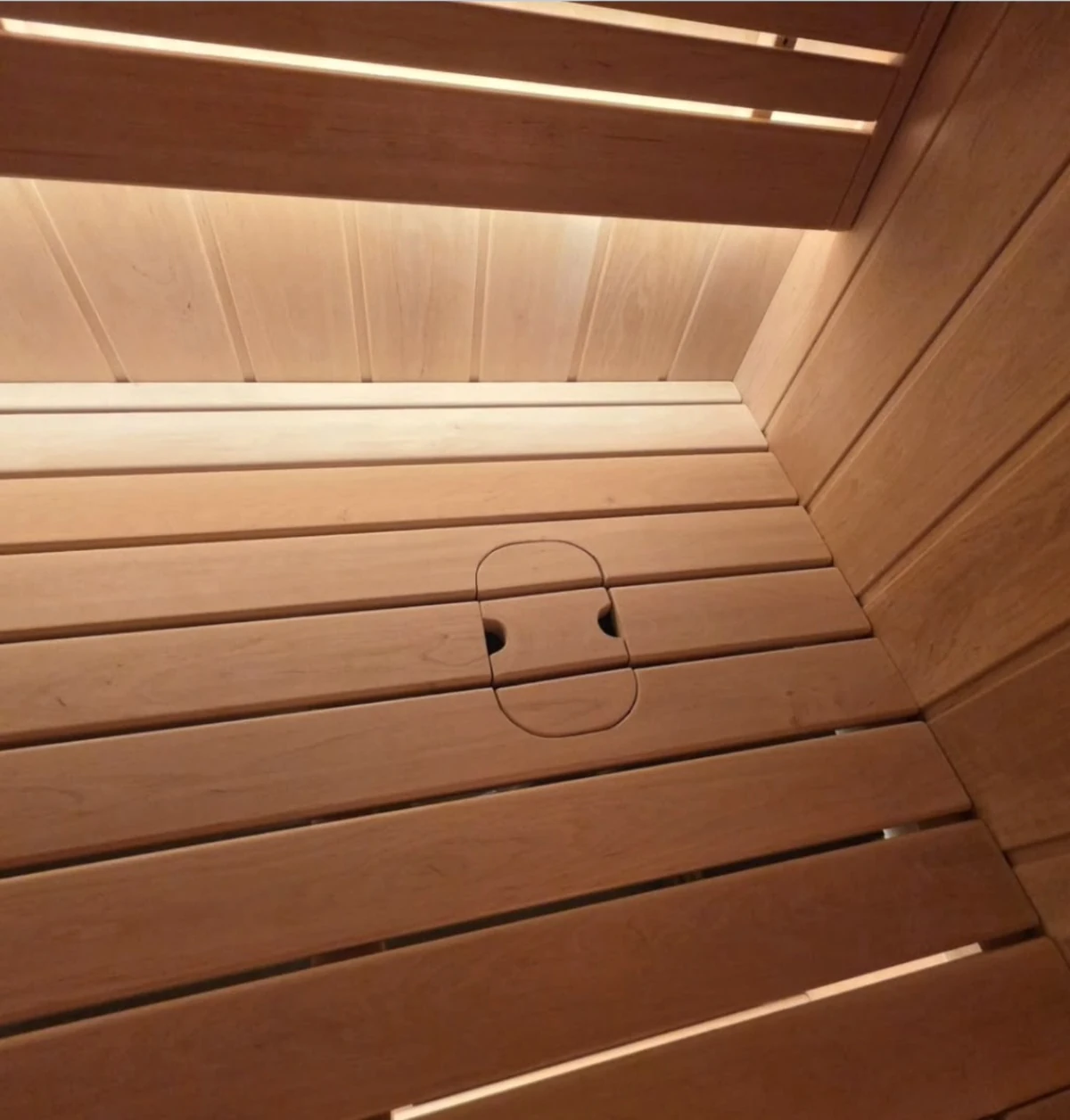 Fresh-Air Breathing System concealed beneath a flush wood cover in the sauna bench