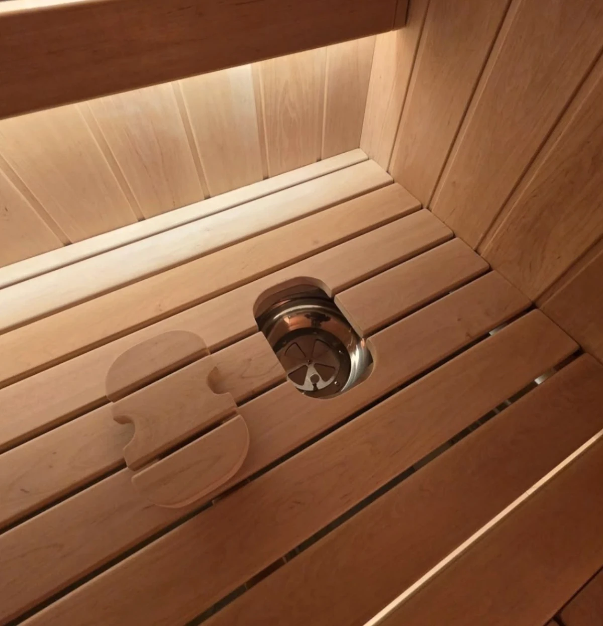 Open fresh-air breathing outlet integrated into the wooden sauna bench