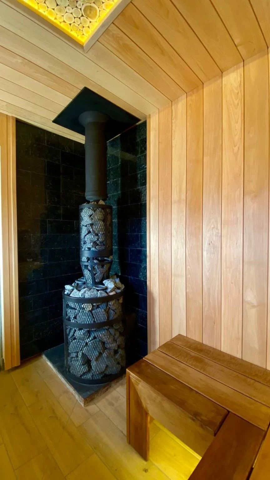 Wood-burning heater and black chimney in a dark stone-lined recess