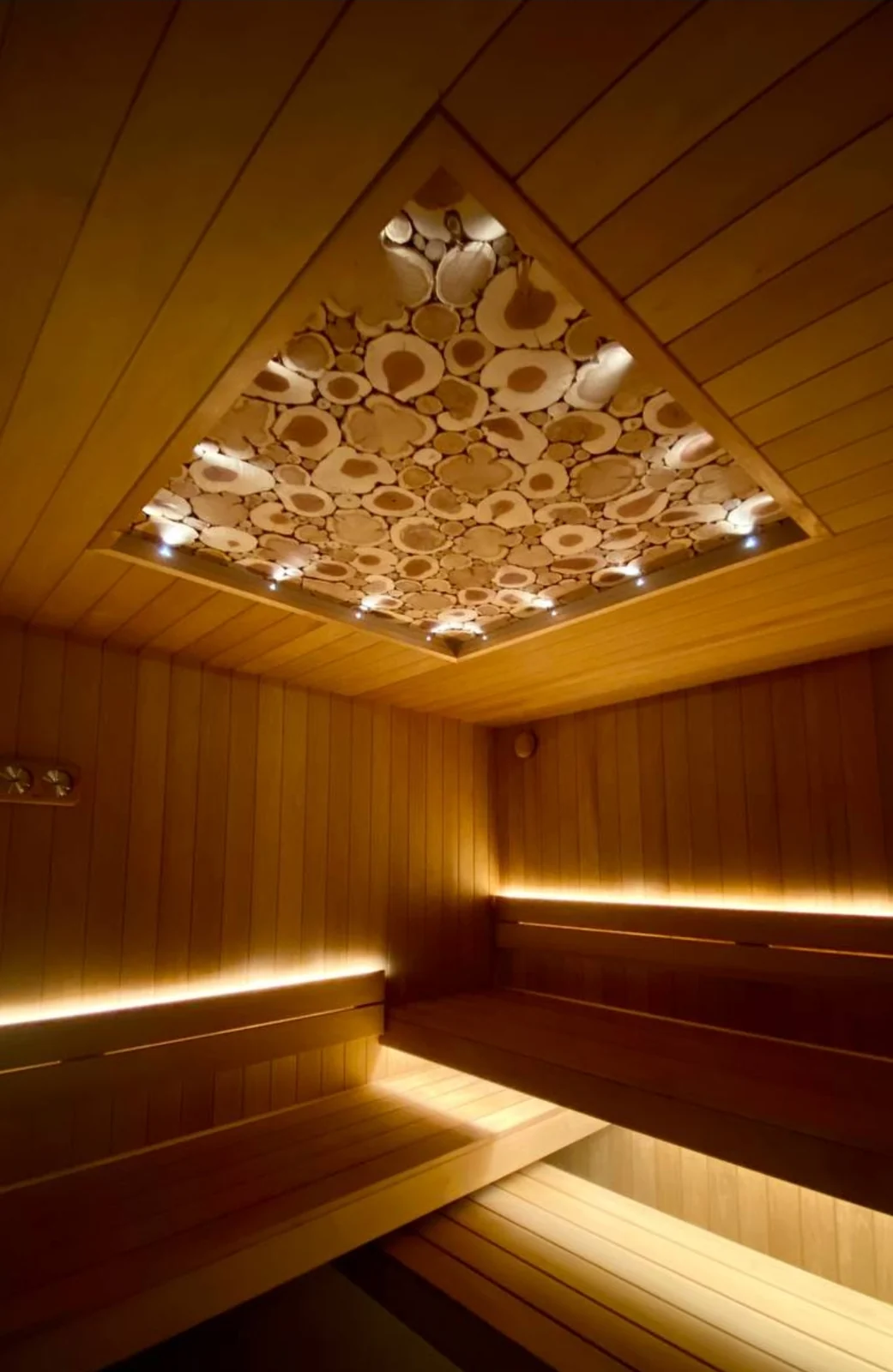 Finished private sauna with illuminated wood-slice ceiling and corner benches